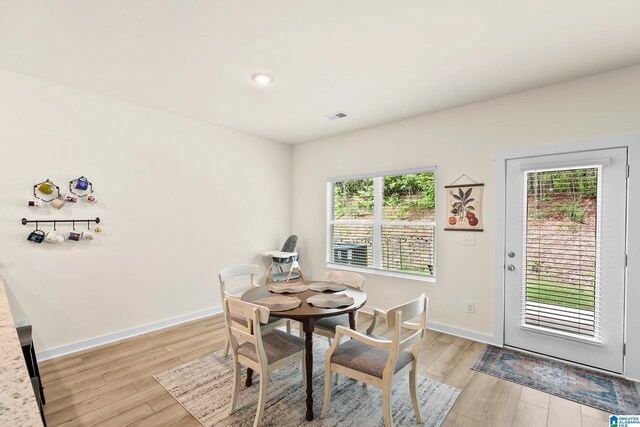 dining space featuring light wood-style floors, baseboards, and visible vents