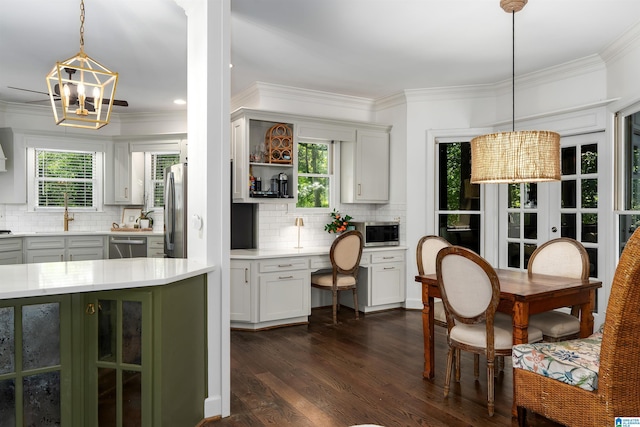 kitchen featuring decorative backsplash, ornamental molding, light countertops, dark wood finished floors, and stainless steel appliances
