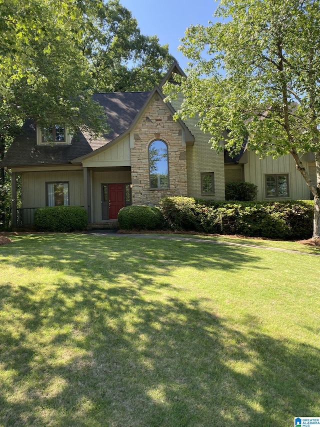 view of front of property featuring board and batten siding, stone siding, and a front lawn