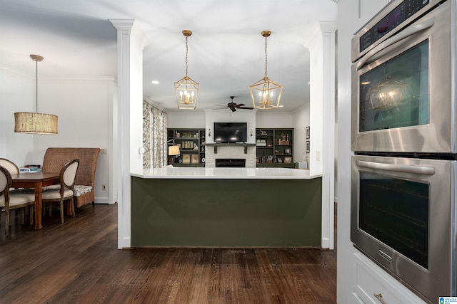 kitchen featuring ornamental molding, decorative light fixtures, double oven, and dark wood-type flooring