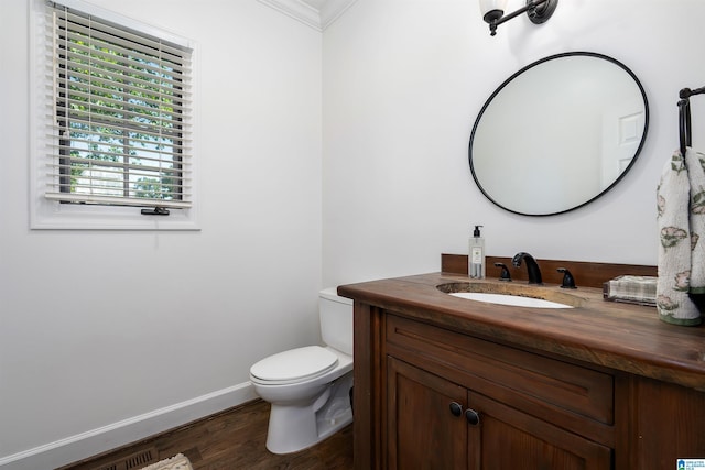 bathroom with vanity, ornamental molding, wood finished floors, toilet, and baseboards