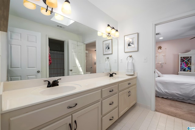 bathroom with double vanity, visible vents, tile patterned flooring, a sink, and connected bathroom
