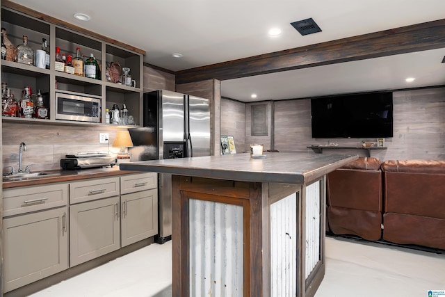 kitchen with open floor plan, tasteful backsplash, a sink, wood counters, and appliances with stainless steel finishes