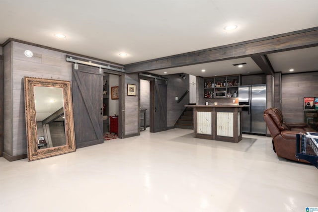interior space with stairs, a barn door, stainless steel fridge with ice dispenser, bar area, and recessed lighting