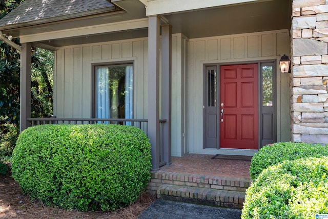 doorway to property featuring roof with shingles and stone siding