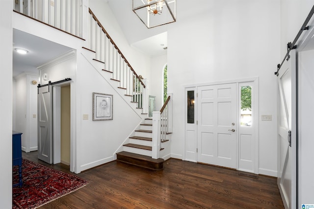 foyer with a high ceiling, dark wood finished floors, a barn door, and stairway