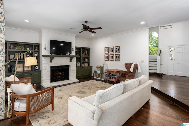living area featuring a stone fireplace, dark wood finished floors, ceiling fan, and stairway