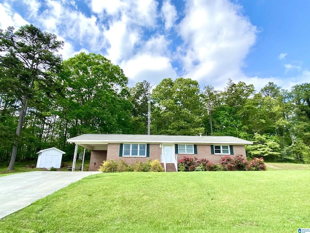 single story home featuring brick siding, driveway, a shed, and a front yard