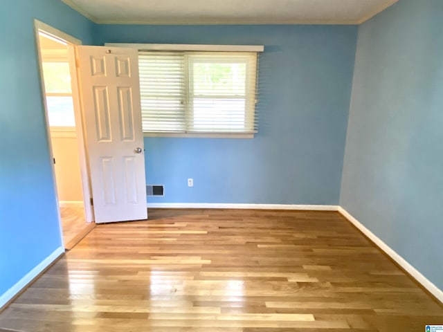 spare room featuring visible vents, ornamental molding, baseboards, and wood finished floors