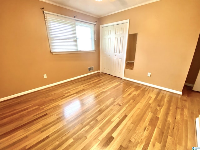 unfurnished bedroom featuring crown molding, baseboards, wood finished floors, and visible vents
