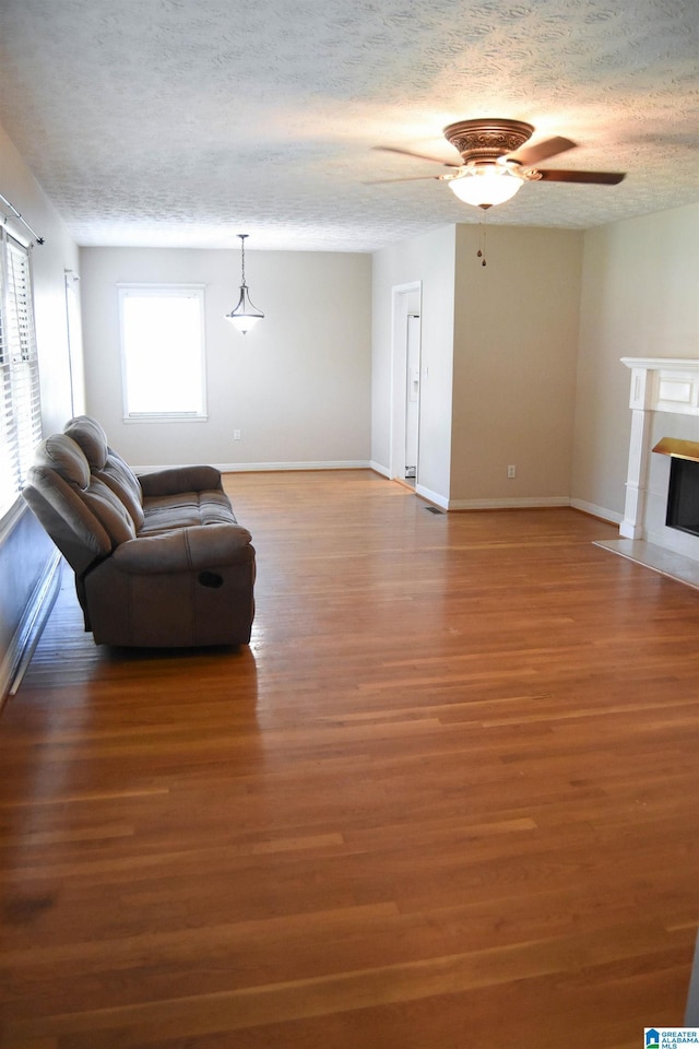 602 Riddle Ave, Piedmont, AL 36272 - living area with ceiling fan, a textured ceiling, a fireplace with flush hearth, wood finished floors, and baseboards