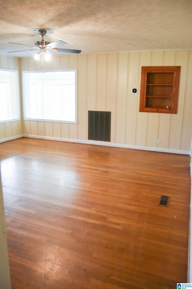 602 Riddle Ave, Piedmont, AL 36272 - empty room featuring visible vents, ceiling fan, wood finished floors, and a decorative wall
