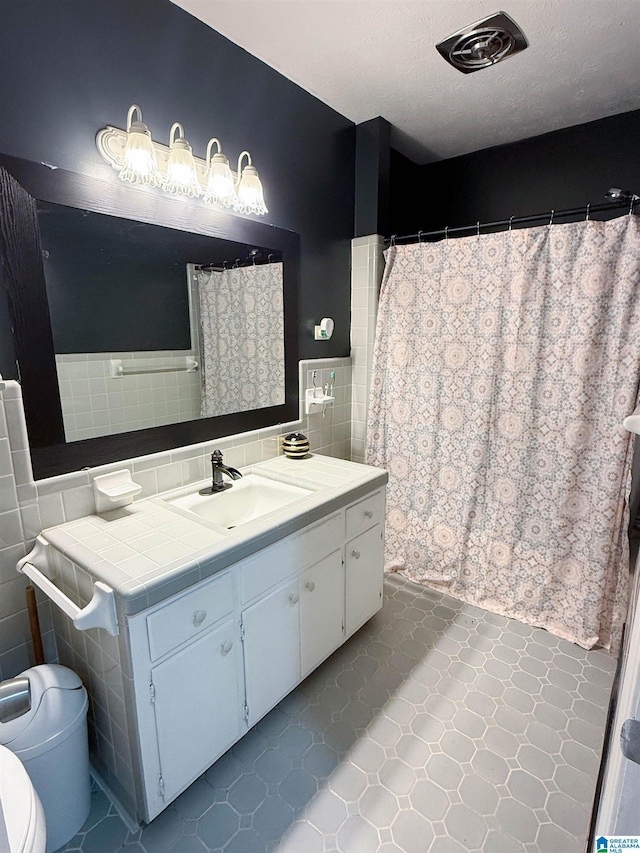 602 Riddle Ave, Piedmont, AL 36272 - full bath with vanity, curtained shower, toilet, tile walls, and a textured ceiling