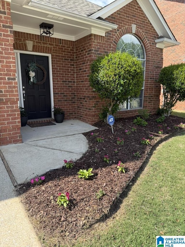 property entrance featuring brick siding and a shingled roof