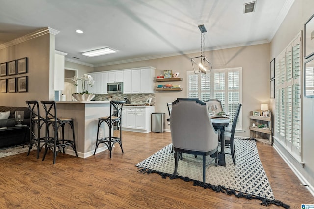 dining area with crown molding, recessed lighting, wood finished floors, and visible vents