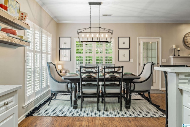 dining space featuring visible vents, ornamental molding, wood finished floors, baseboards, and a chandelier
