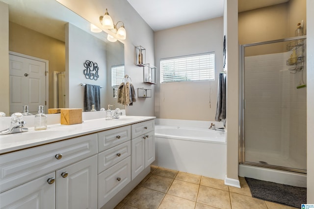 bathroom with double vanity, a bath, a stall shower, a sink, and tile patterned floors