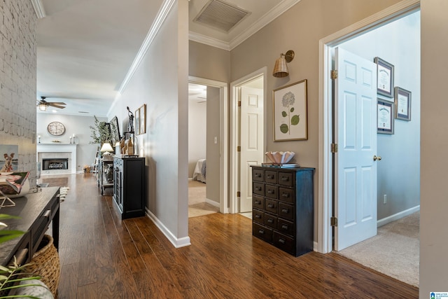 hall featuring crown molding, baseboards, visible vents, and dark wood finished floors