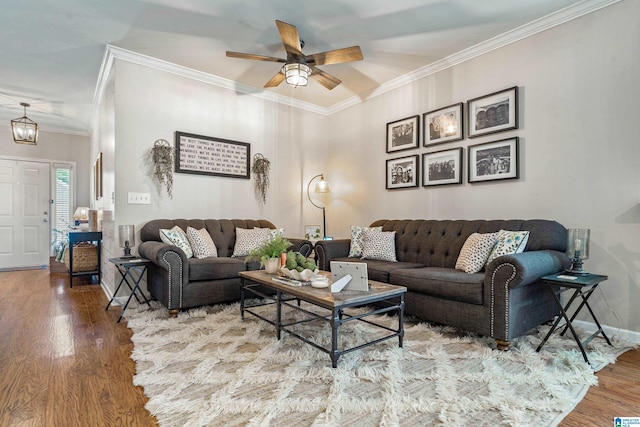 living area featuring baseboards, ornamental molding, ceiling fan, and wood finished floors