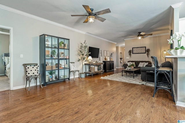 living room with a ceiling fan, baseboards, ornamental molding, and wood finished floors