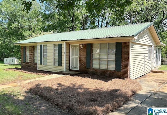 ranch-style house featuring brick siding, metal roof, and a front lawn