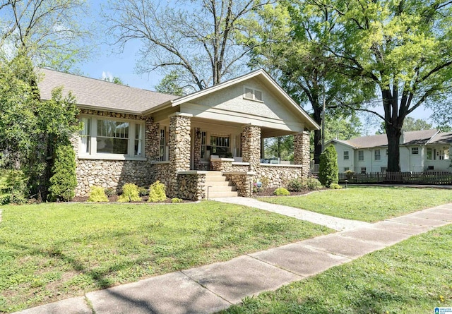 530 10th Ave S, Birmingham, AL 35205 - view of front facade featuring fence, covered porch, a front lawn, and stone siding