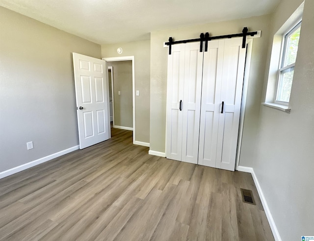 5482 Hackberry Ln N, Gadsden, AL 35903 - unfurnished bedroom featuring baseboards, a closet, light wood-type flooring, and a barn door