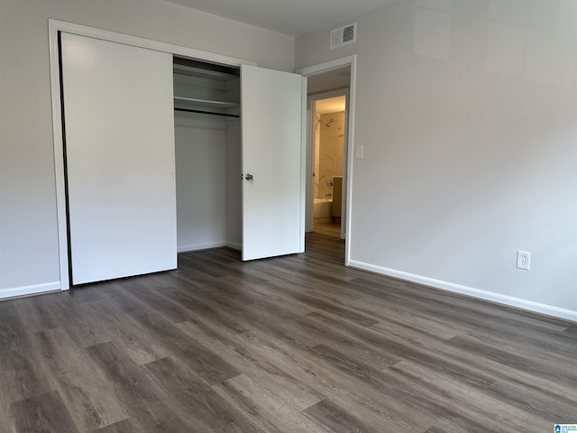 unfurnished bedroom featuring visible vents, baseboards, dark wood-style floors, and a closet