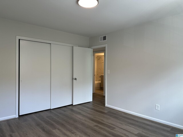 unfurnished bedroom with baseboards, a closet, dark wood finished floors, and visible vents