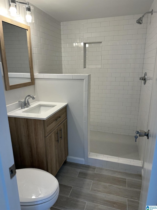 bathroom featuring vanity, wood tiled floor, a shower stall, and toilet