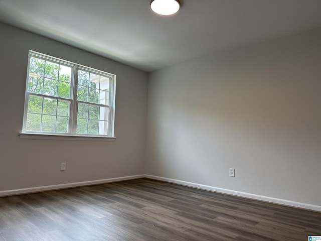 unfurnished room featuring a healthy amount of sunlight, baseboards, and dark wood-style flooring