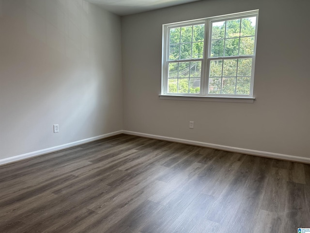 unfurnished room featuring baseboards and dark wood-type flooring