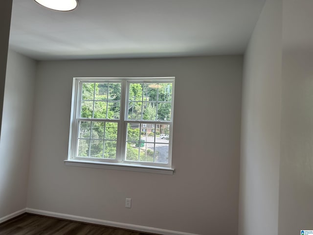 spare room featuring baseboards and dark wood-type flooring