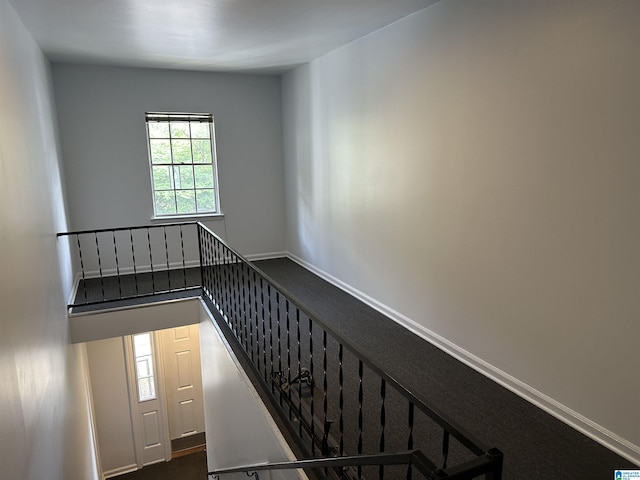 stairway with baseboards and carpet flooring