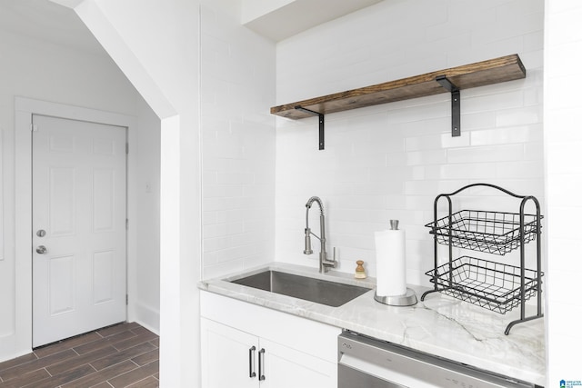 kitchen featuring light stone countertops, a sink, dishwasher, white cabinetry, and dark wood-style floors