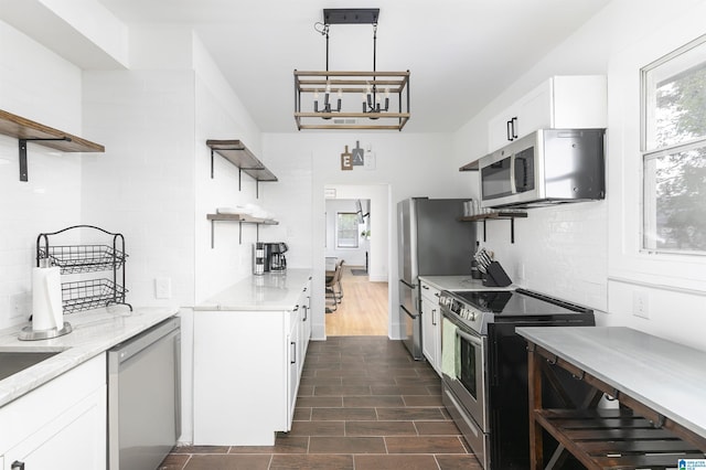 kitchen with open shelves, appliances with stainless steel finishes, decorative backsplash, and a healthy amount of sunlight