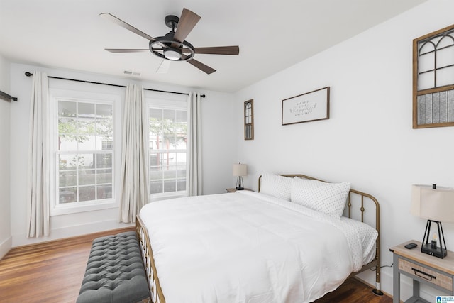 bedroom featuring baseboards, ceiling fan, wood finished floors, and visible vents