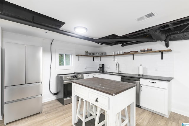 kitchen featuring white cabinets, open shelves, appliances with stainless steel finishes, a sink, and visible vents