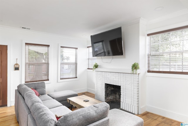 living room featuring a brick fireplace, visible vents, ornamental molding, and a wealth of natural light