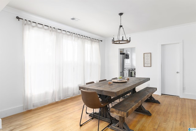 dining room featuring visible vents, light wood-style floors, and crown molding