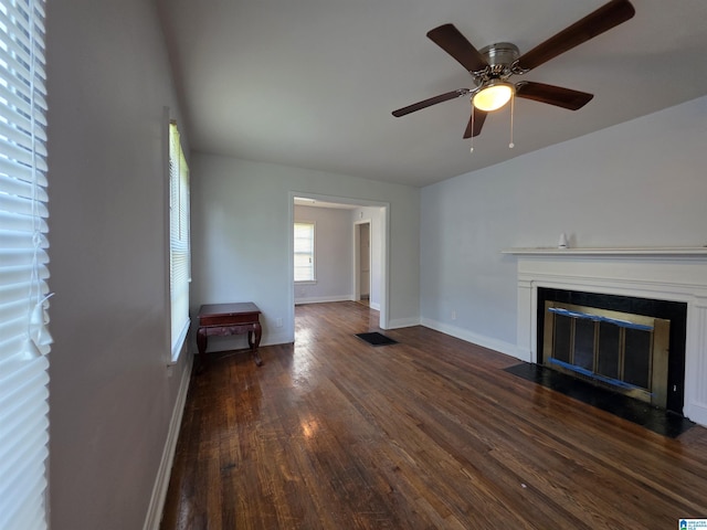 unfurnished living room with ceiling fan, baseboards, a fireplace with flush hearth, wood finished floors, and visible vents