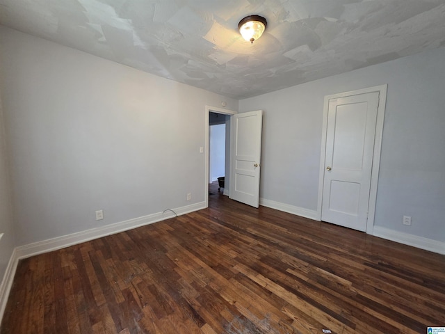 unfurnished bedroom with baseboards and dark wood-style flooring