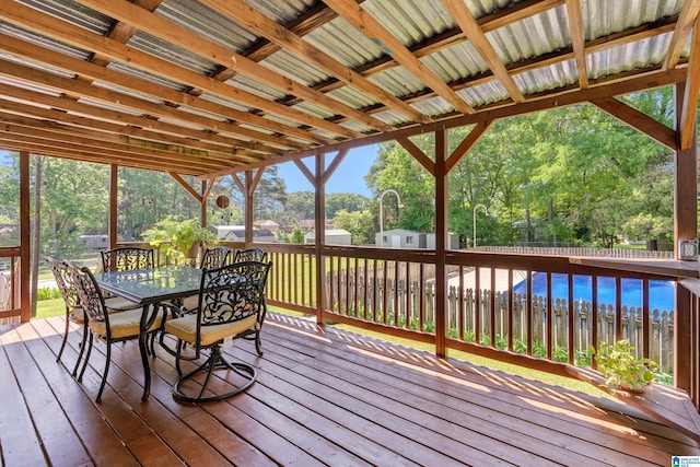 deck with fence, an outbuilding, outdoor dining space, and a storage unit