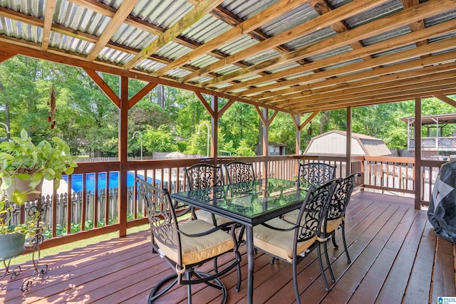 wooden deck with a storage unit, an outdoor structure, a fenced backyard, and outdoor dining space
