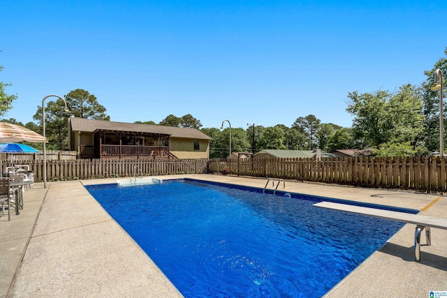 view of swimming pool featuring a fenced in pool, a diving board, fence, and a patio