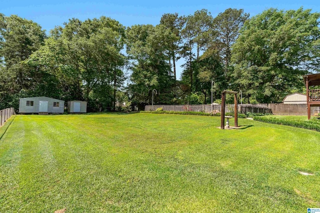 view of yard featuring a fenced backyard, a storage unit, and an outdoor structure