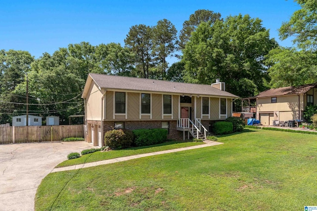 bi-level home featuring fence, a chimney, brick siding, concrete driveway, and an attached garage