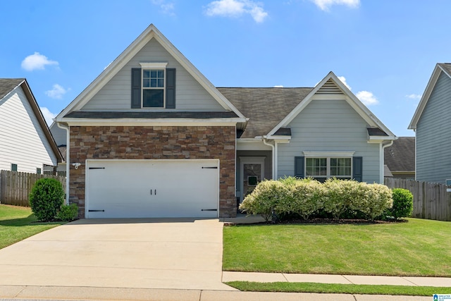 craftsman-style house with concrete driveway, a front yard, fence, and stone siding