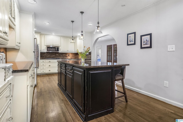 1856 Southwood Rd, Vestavia Hills, AL 35216 - kitchen with a kitchen breakfast bar, appliances with stainless steel finishes, tasteful backsplash, arched walkways, and white cabinetry