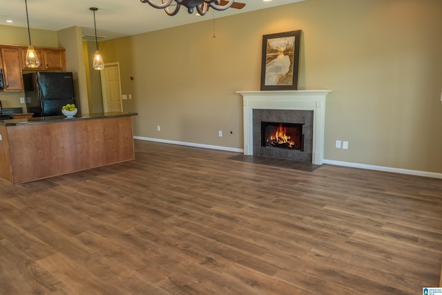 unfurnished living room with dark wood-style flooring, baseboards, and a tile fireplace